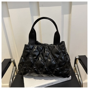 Détail du sac cabas matelassé noir sur une chaise montrant la texture brillante du nylon