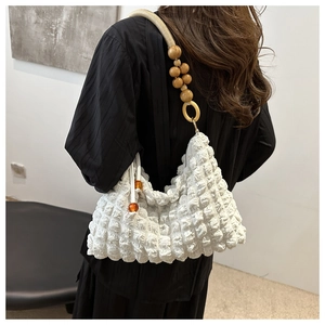 Détail du sac blanc texturé avec bandoulière en perles de bois et pendentif ambré