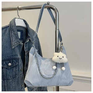 Detail of light blue hobo bag with water-ripple texture and white cloud plush charm