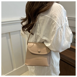 Detail of minimalist beige crossbody bucket bag with fashion lettering and matte leather texture