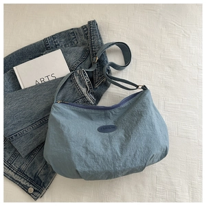 Detail of blue tote bag showing the pleated texture fabric and fashion logo patch