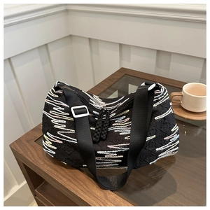 Detail of black fabric tote bag with colorful wavy embroidery and adjustable nylon strap