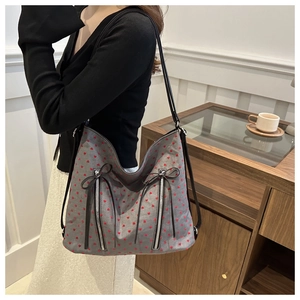 Detailed close-up of grey tote bag with red heart patterns and decorative bow knots