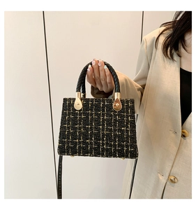 Close-up of black and gold tweed handbag featuring metallic feet and refined chain details