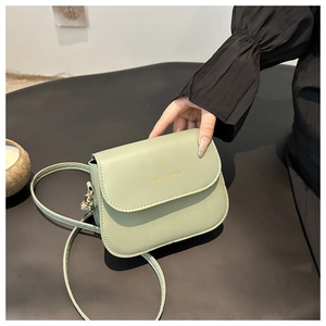 Detailed close-up of light green PU leather bag with gold embossed brand logo and strap