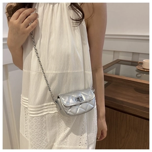 Détail du sac bandoulière argenté matelassé avec chaîne en métal et fermoir rotatif