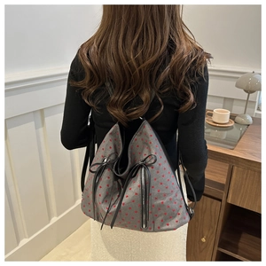 Detail eines grauen Canvas-Rucksacks mit roten Herz-Prints und schwarzen Schleifen-Zippern