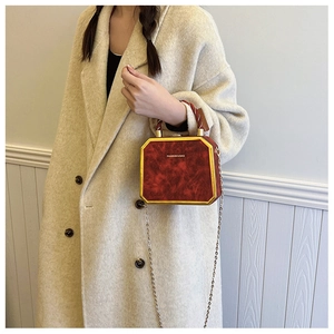 Detail van rode vintage box bag met goudkleurig frame, geweven handvat en gouden ketting