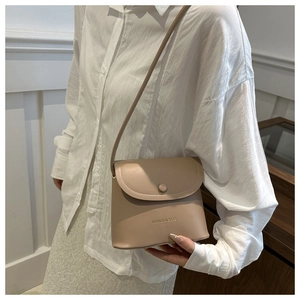 Close-up of minimalist beige leather crossbody bag with flap and button closure details
