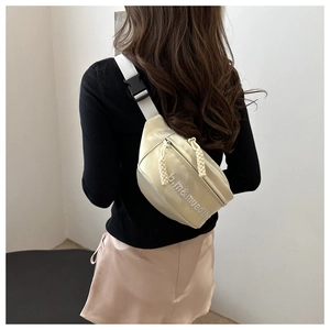Detail view of cream crossbody bag featuring letter print and adjustable buckle strap