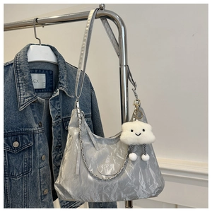 Detail of silver metallic hobo bag with a plush cloud charm and silver chain decoration