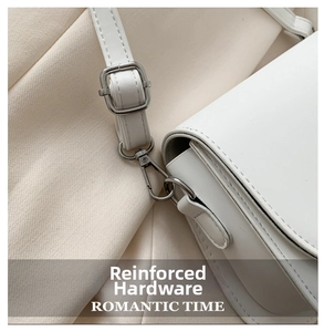 Detailed shot of silver adjustable buckle and sturdy hardware on a white saddle bag