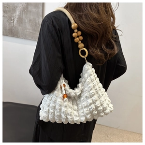 Détail du sac blanc texturé avec bandoulière en perles de bois et anneaux dorés