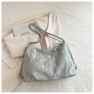 Detail view of the light blue wrinkled texture and minimalist logo on this large tote bag