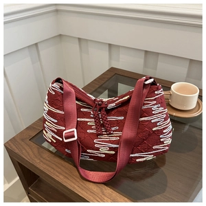 Close-up of burgundy tote bag with wave embroidery and wide nylon shoulder strap