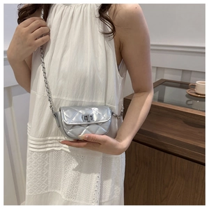 Petit sac bandoulière argenté matelassé avec chaîne métallique porté par un mannequin