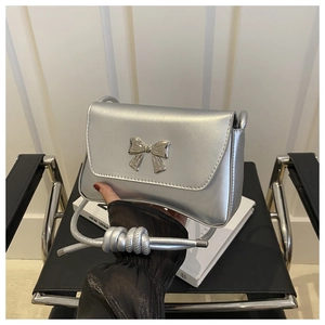 Détail du sac bandoulière argenté avec boucle nœud et bandoulière à nœuds design