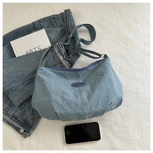 Detailed top view of light blue ruched shoulder bag with Fashion label and accessories