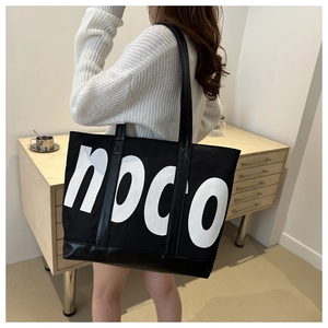 Detail of large black tote bag with white noco print and leather stitching accents