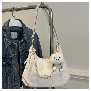 Detail of white cloud pleated tote bag featuring a metal chain and plush charm