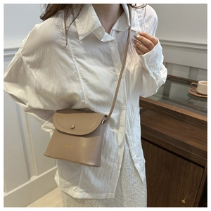 Detailed close-up of a minimalist beige bucket bag with adjustable shoulder strap