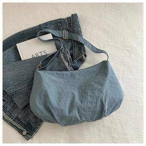 Close-up of light blue wrinkled nylon tote with adjustable strap and metal buckle