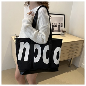 Detailed side view of a large black nylon travel tote featuring a bold hogo print