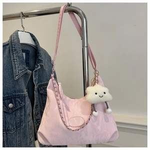 Pink hobo bag with silver chain detail and white plush cloud charm hanging on a rack