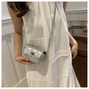 Détail d'un mini sac bandoulière argenté matelassé avec chaîne et fermoir rotatif