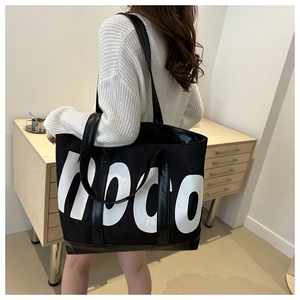 Rear view of a model wearing a large black tote bag with white HOCO letter print