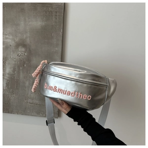 Detail of silver metallic waist bag with pink embroidered letters and woven zipper puller
