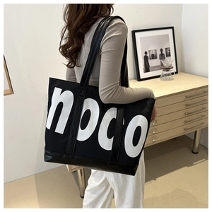 Model view of large black tote bag with white noco letter print in a modern room