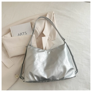 Close-up of silver metallic tote bag with crinkled texture on a beige blazer background