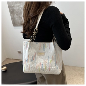 Détail du sac cabas blanc avec broderies verticales colorées et bandoulière en chaîne