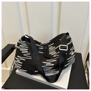 Detailed close-up of a black pleated tote with colorful zigzag embroidery and wide nylon strap