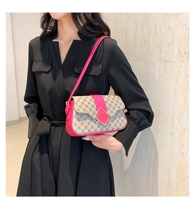 Sac à bandoulière en cuir magenta avec motif monogramme vintage porté par un mannequin