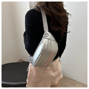 Close-up of metallic silver crossbody bag with pink embroidered letters and woven zipper pull