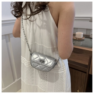 Mini sac bandoulière argenté matelassé avec chaîne en métal et fermoir porté par un mannequin