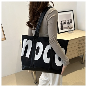 Close-up of the large capacity canvas tote bag with white letter print and leather strap