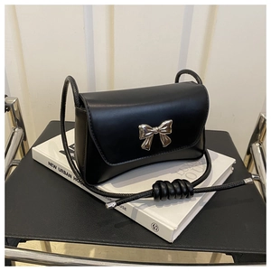Détail du nœud argenté et de la bandoulière nouée sur un sac minimaliste en cuir noir
