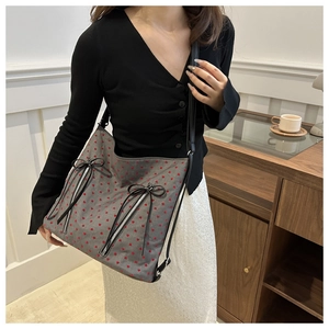 Detail of grey tote bag with red heart pattern, vertical zippers and black bows