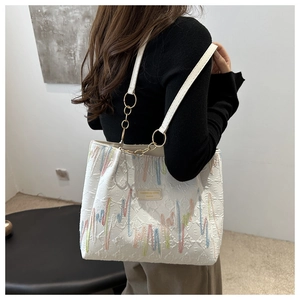 Détail du sac cabas blanc avec broderie colorée et bandoulière en cuir à chaîne dorée