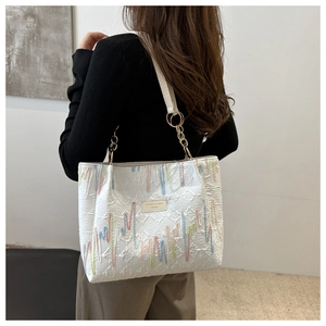 Détail du sac cabas matelassé avec broderies colorées et bandoulière chaîne dorée
