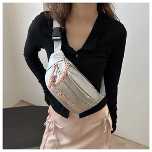 Détail du sac bandoulière argenté métallisé avec tirettes roses et imprimé logo