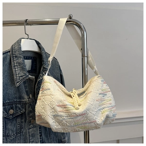 Detail of white canvas dumpling bag featuring colorful wavy embroidery and embossed patterns