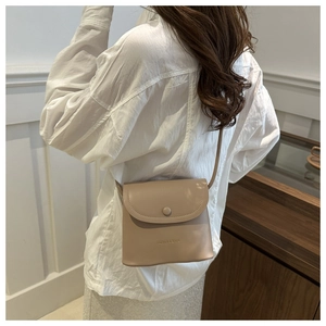 Detailed side view of a beige minimalist square crossbody bag with flip cover on model