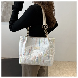 Détail du sac cabas blanc avec broderies ondulées, anneau en métal et bandoulière en cuir