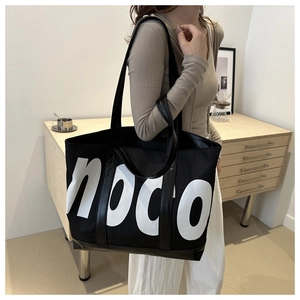 Close-up of a large black nylon tote bag with white noco print and leather handles