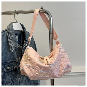 Detailed view of pink dumpling bag featuring textured brand pattern and wavy stitching