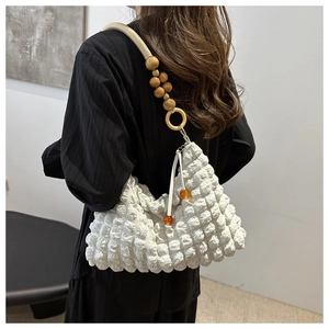 Détail du sac blanc à texture bulle avec perles en bois et accents de résine sur la bandoulière